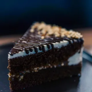 A slice of layered chocolate hazelnut cake, plated with cream.