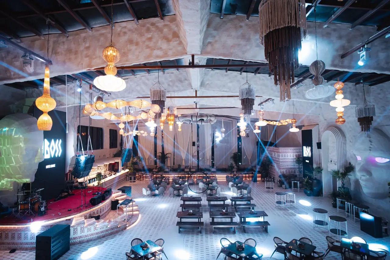 Blue beams crossing the floor at night, the red stage at one end and tasselled chandeliers hanging the length of the room.